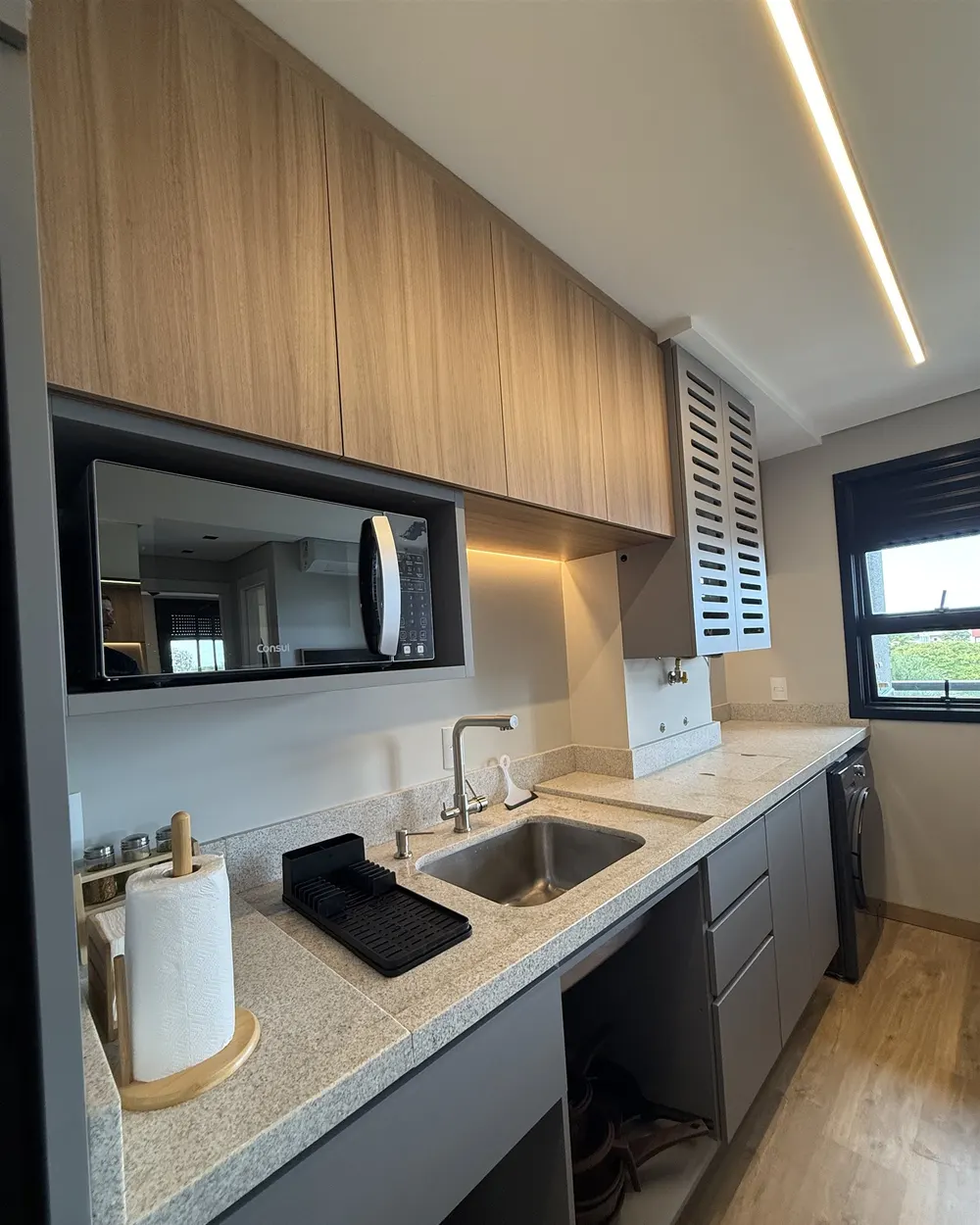 Cozinha com marcenaria em madeira e grafite e iluminação embutida – Apartamento N+R, Capão da Canoa/RS