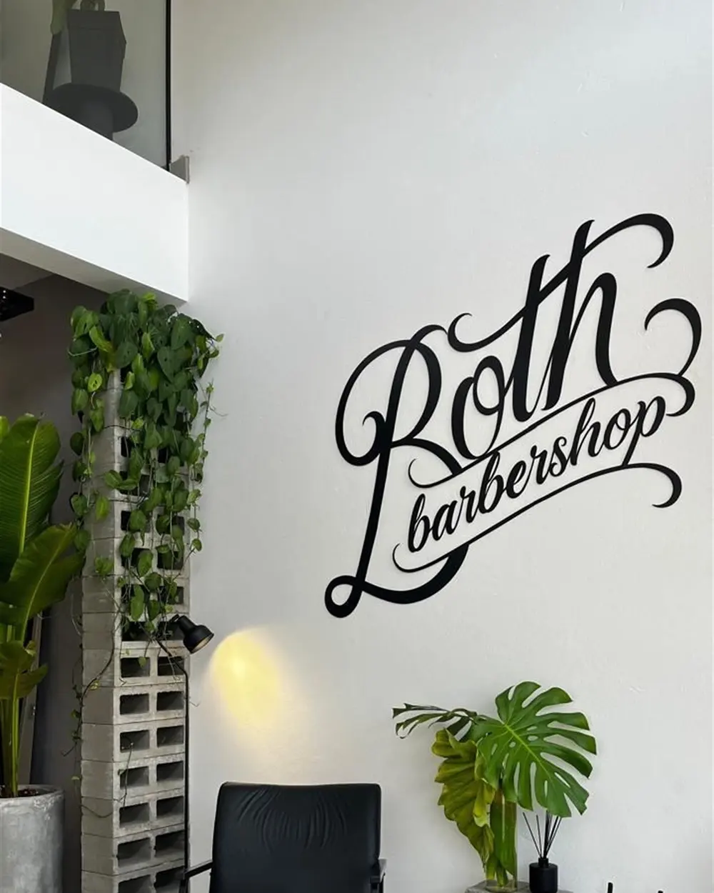 Parede assinada Both Barbershop com poltronas de espera