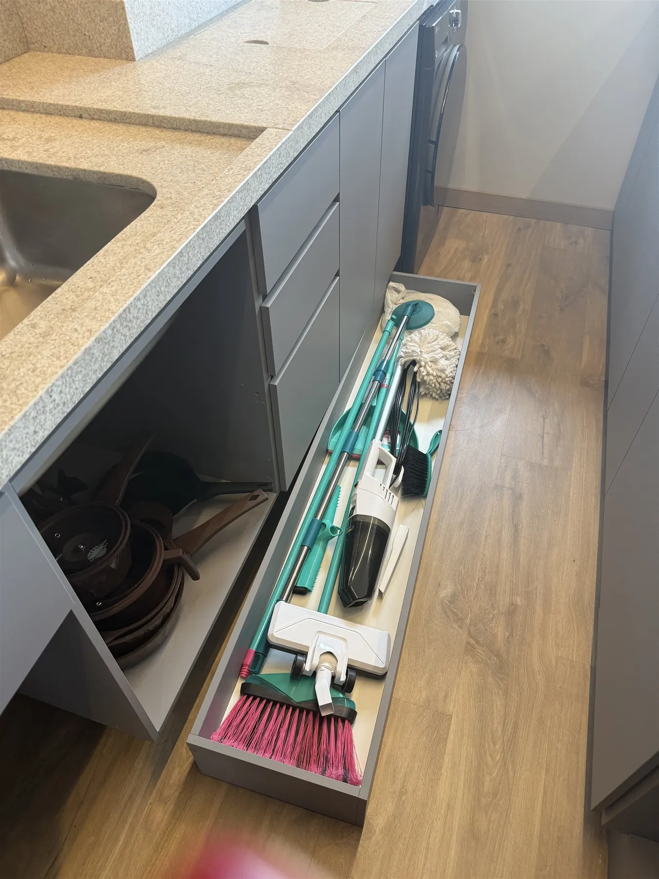 Gaveta organizadora com utensílios de limpeza, aspirador e vassouras