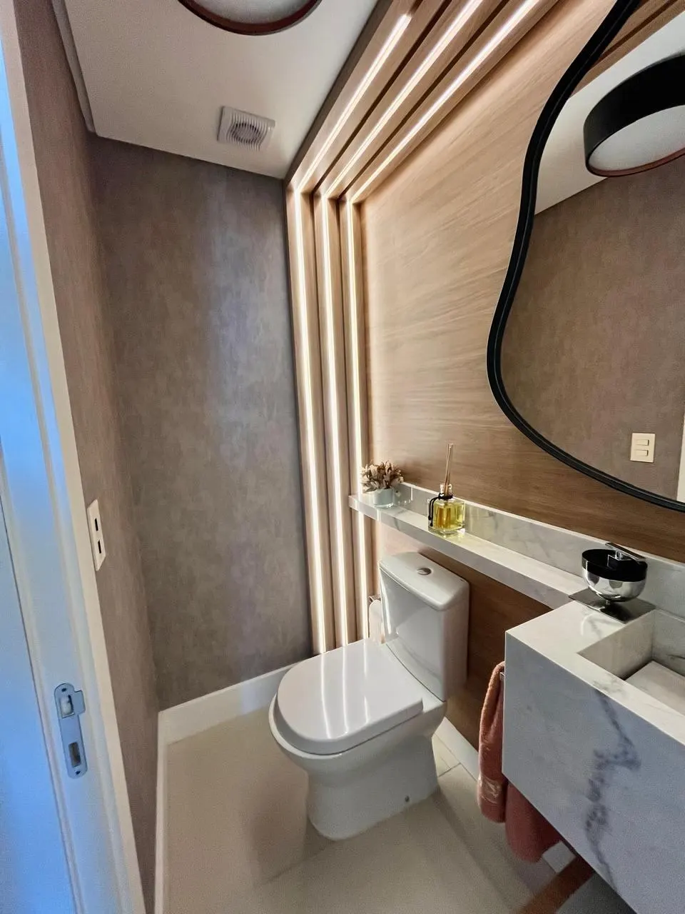 Pronto – O mesmo lavabo pronto, com o painel ripado e a iluminação linear acesa, Lavabo Miriam (Torres/RS)