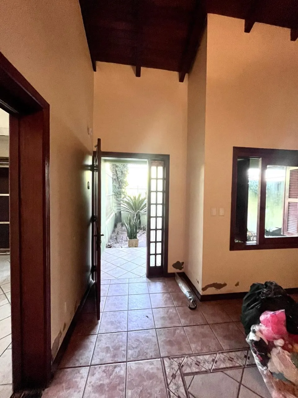 Antes – Corredor de entrada antes da reforma, vazio, apenas com a porta de madeira, Sobrado pós-enchente (Canoas/RS)