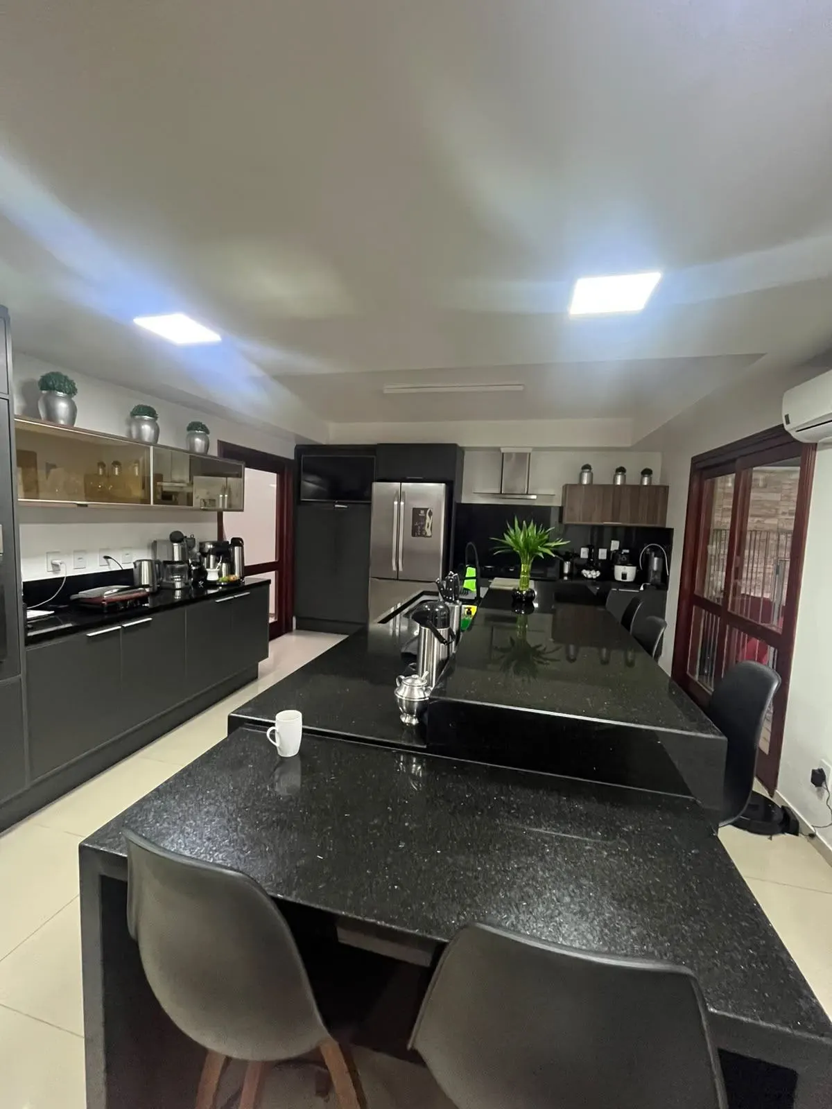 Depois – Cozinha pronta, ilha em pedra escura e eletrodomésticos integrados, Sobrado pós-enchente (Canoas/RS)